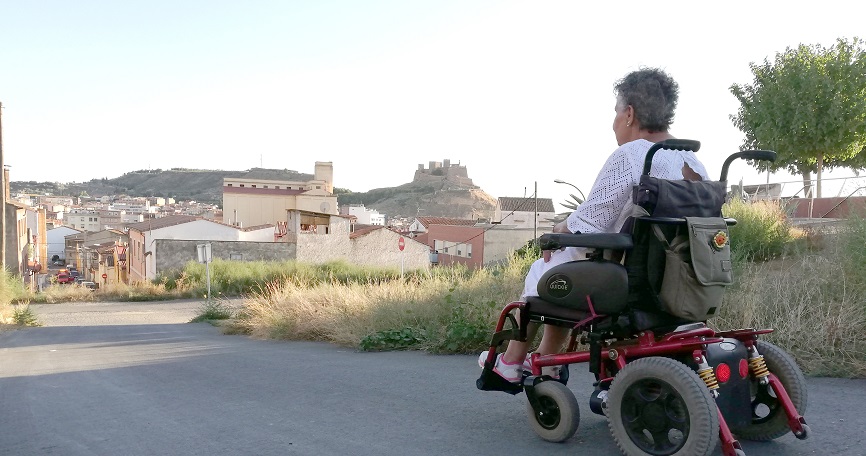 Persona en silla de ruedas circulando por asfalto en ámbito rural